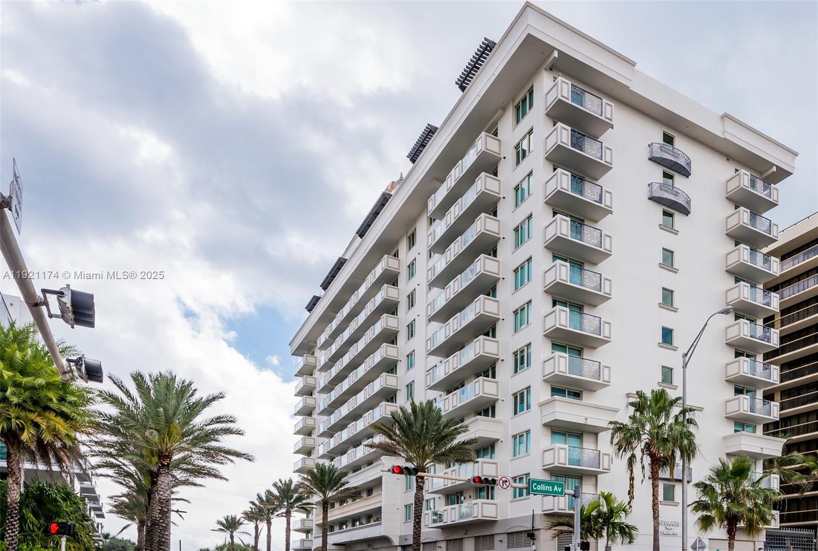 A multi-story white residential building stands along a street with palm trees and traffic lights — 9499 Collins Avenue # 02, Surfside FL 33154, SURFSIDE, FL