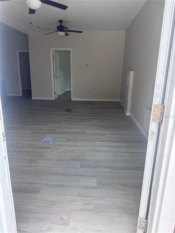 An interior view of a room with light wood-look flooring and two ceiling fans — 32 ADA STREET, TARPON SPRINGS, FL