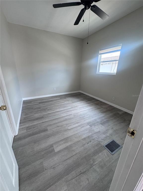 A bedroom features light gray walls, wood-look flooring, a ceiling fan, and a single window — 32 ADA STREET, TARPON SPRINGS, FL