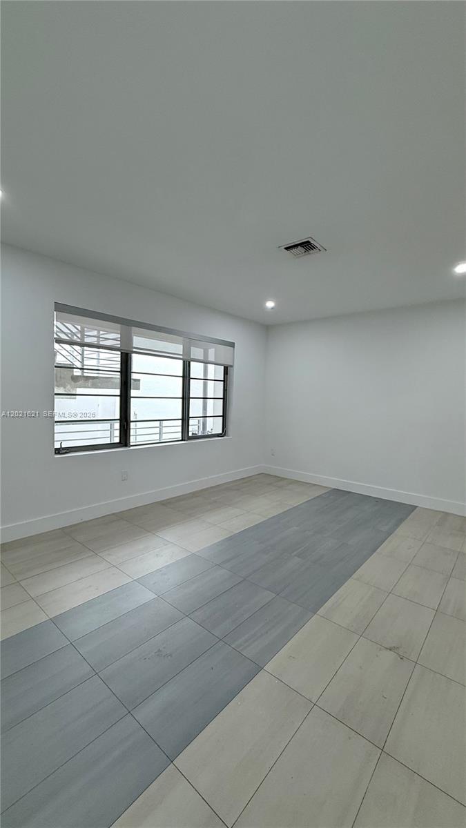 An empty room features white walls, recessed lighting, and a floor with light and dark tiles — 2021 Meridian Ave # 6, Miami Beach FL 33139, MIAMI BEACH, FL