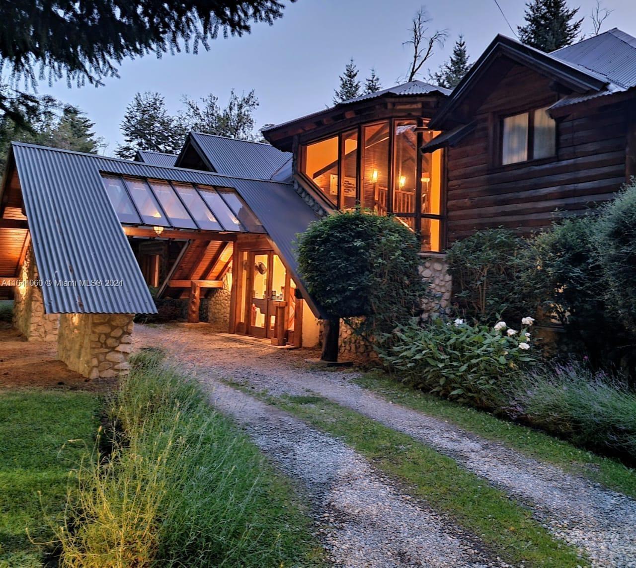 A rustic log cabin with a metal roof, stone base, and a glass-enclosed entryway — ARGENTINA Puerto Manzano Villa La Angostura, FL