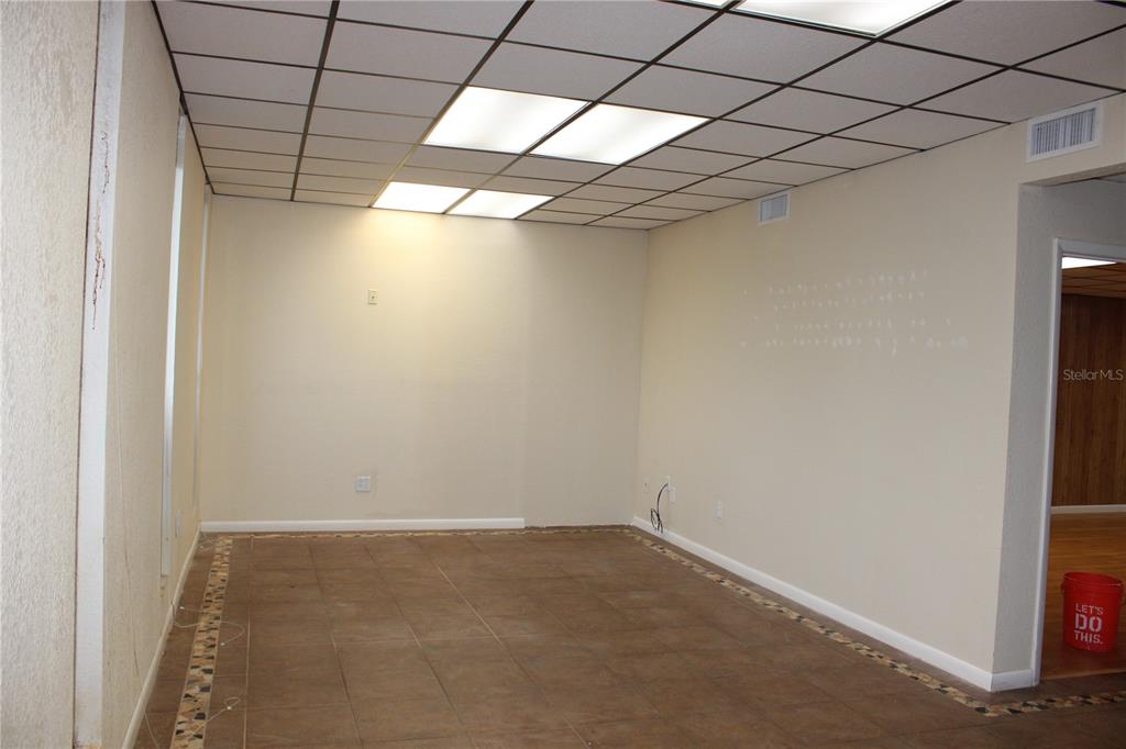 An empty office room features a drop ceiling with recessed lighting and brown tile flooring — 1224 66TH STREET N UNIT 1234,1238,1240, ST PETERSBURG, FL