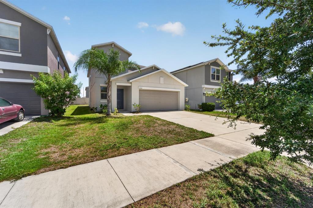 A two-story suburban house with a beige exterior, a two-car garage, and a front lawn — 10210 BOGGY MOSS DRIVE, RIVERVIEW, FL