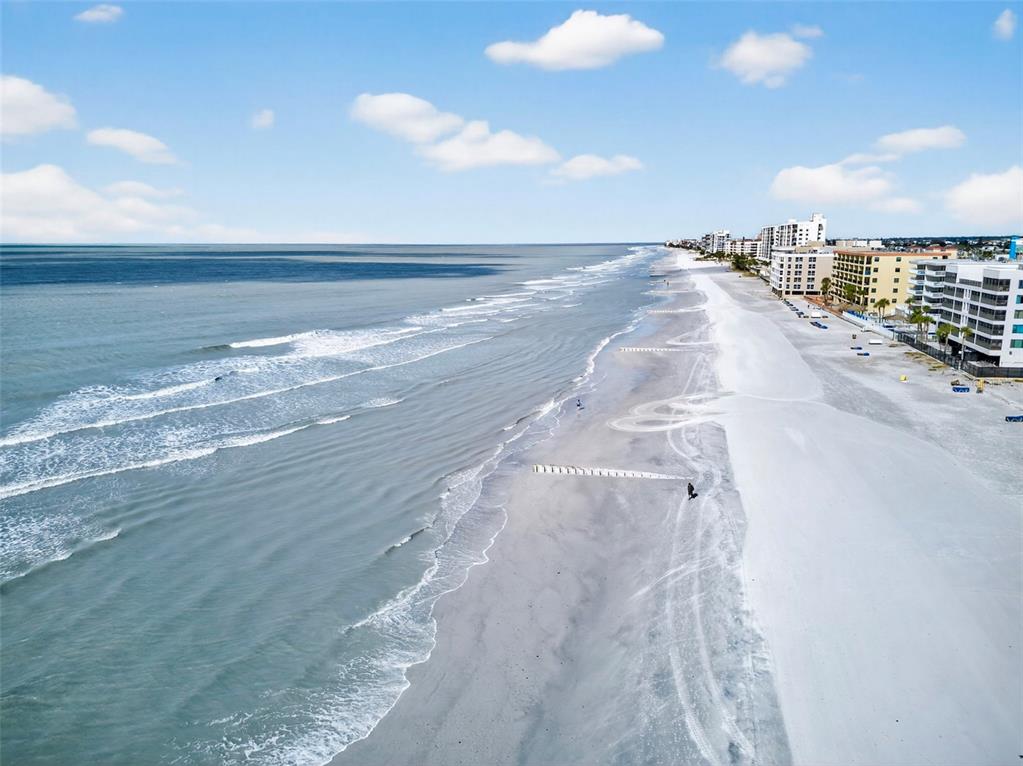 An aerial view of a sandy beach coastline with ocean waves and nearby apartment buildings — 14251 GULF BOULEVARD UNIT 5, MADEIRA BEACH, FL