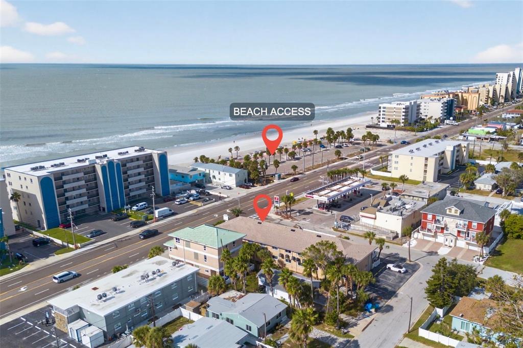 This aerial view shows a coastal area with beach access, nearby hotels, and a gas station — 14251 GULF BOULEVARD UNIT 5, MADEIRA BEACH, FL