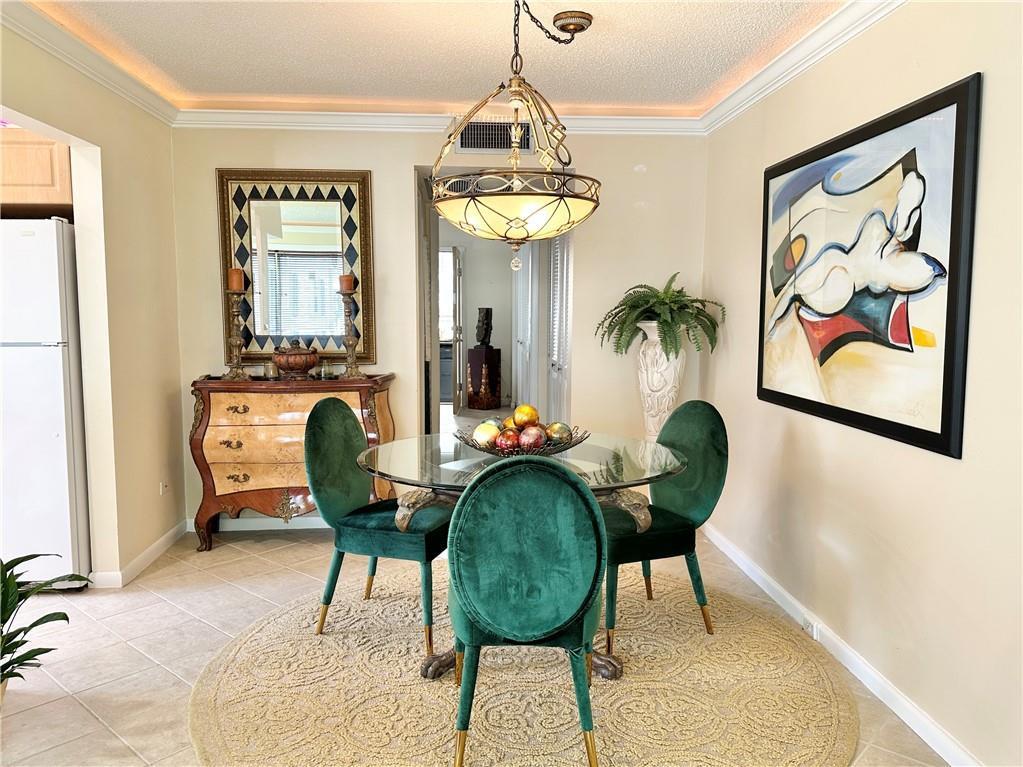 A dining room features a glass-topped table, green velvet chairs, and a decorative chandelier — 285 Oakridge Q # 285, Deerfield Beach FL 33442, DEERFIELD BEACH, FL
