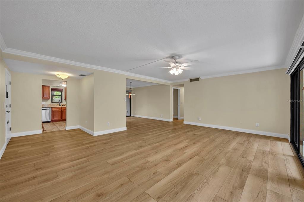A living room features a large white sectional sofa, two round wooden tables, and light-colored flooring — 249 W LAKE FAITH DRIVE UNIT 205, MAITLAND, FL