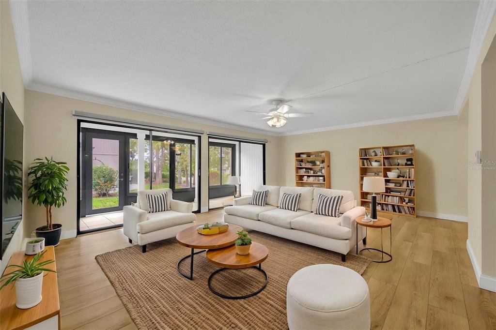 An open-concept living area features light wood-look flooring, beige walls, and a ceiling fan — 249 W LAKE FAITH DRIVE UNIT 205, MAITLAND, FL