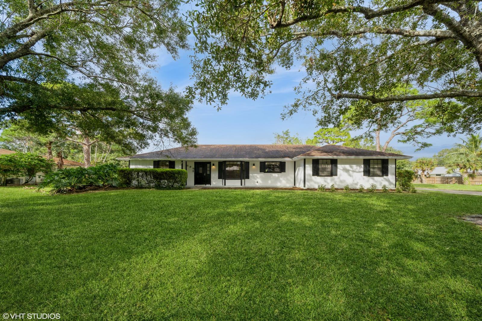 A single-story white house with black shutters and a dark roof sits on a lawn — 595 11th Avenue, Vero Beach FL 32962, VERO BEACH, FL