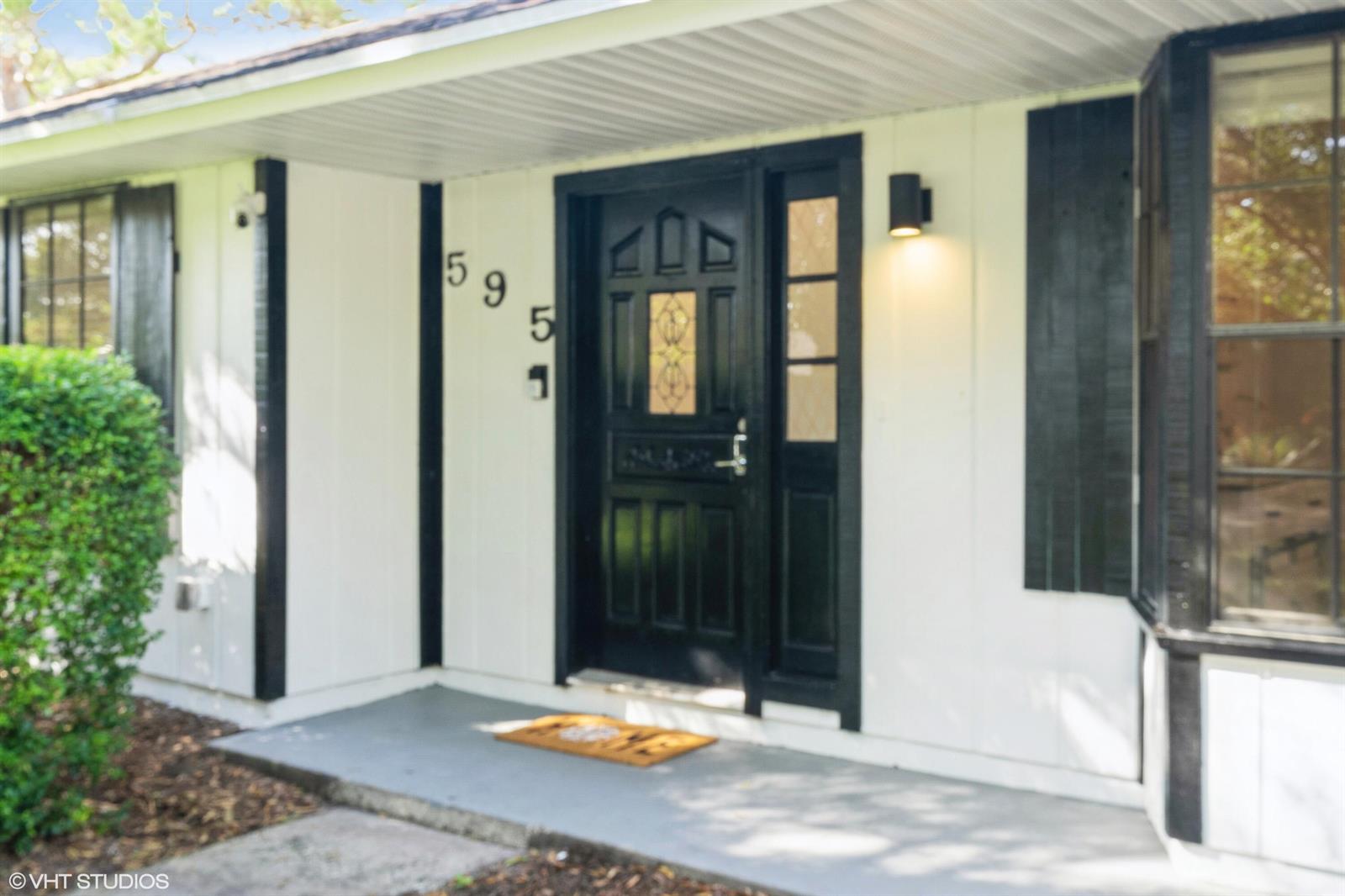A front entrance features a black door with a sidelight and house numbers on white siding — 595 11th Avenue, Vero Beach FL 32962, VERO BEACH, FL