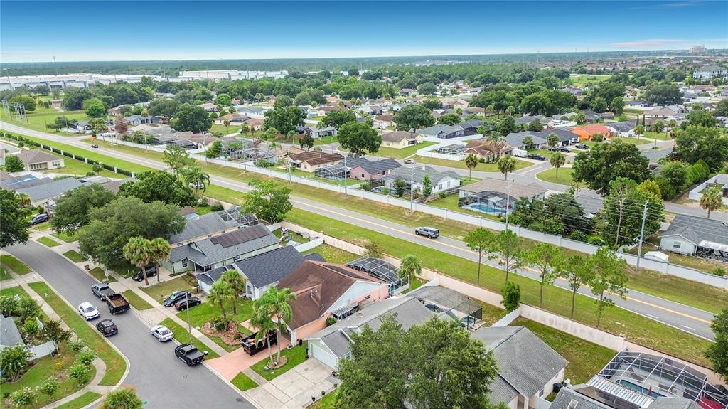 An aerial view shows a suburban neighborhood with houses, swimming pools, and a main road — 7732 WATER OAK CT, KISSIMMEE, FL