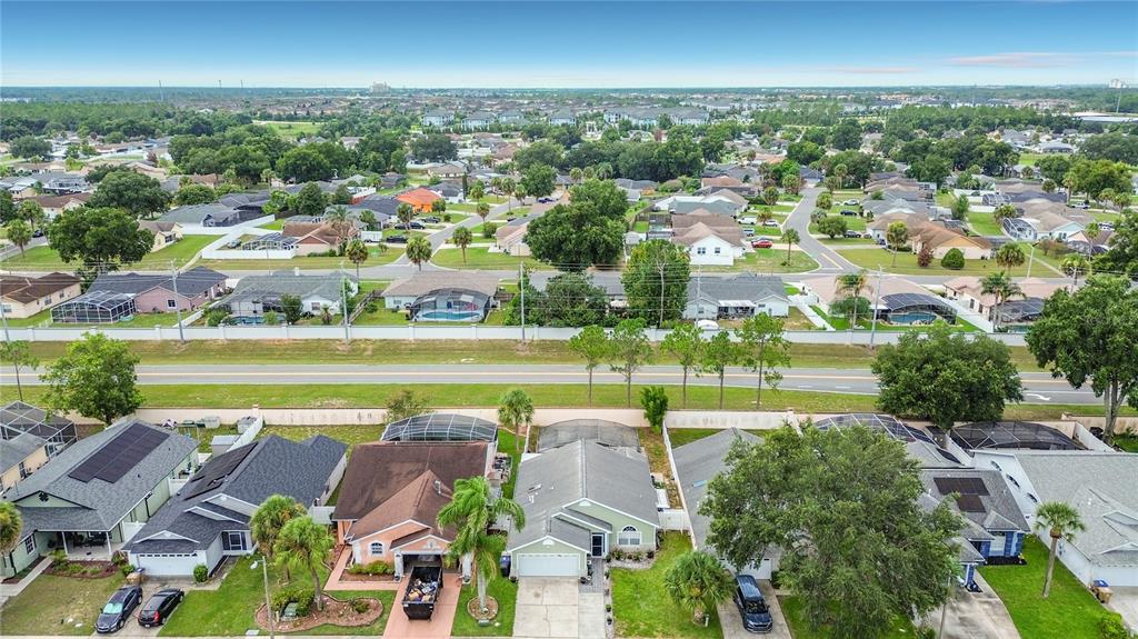 An aerial view shows a suburban neighborhood with houses, swimming pools, and a main road — 7732 WATER OAK CT, KISSIMMEE, FL