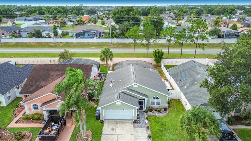 An aerial view shows a green house with a garage and a screened-in back patio — 7732 WATER OAK CT, KISSIMMEE, FL