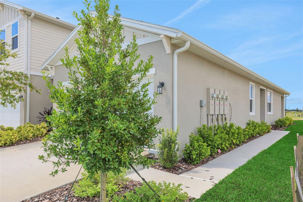 A side view of a beige house exterior with a concrete walkway and landscaping — 7551 SEA OAK COURT, PARRISH, FL