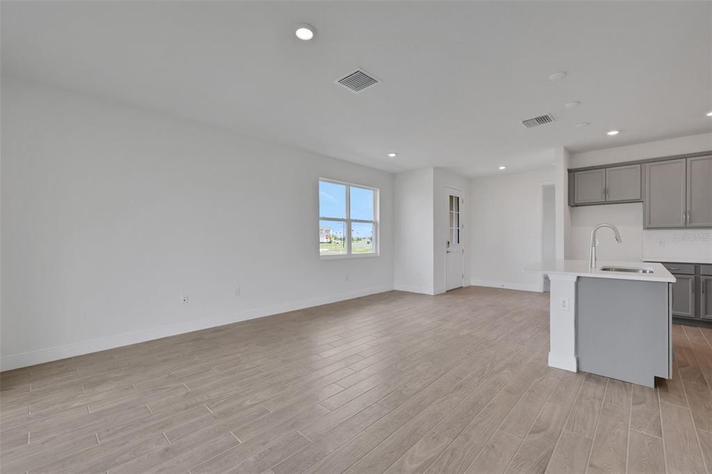 An open-concept living area features light wood-look tile flooring and a kitchen with gray cabinets — 7551 SEA OAK COURT, PARRISH, FL