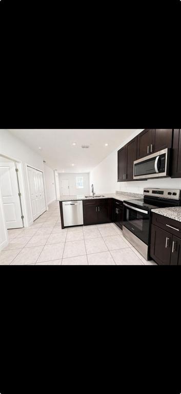 A kitchen features dark wood cabinets, stainless steel appliances, and light tile flooring — 9130 N MENDOZA WAY, CITRUS SPRINGS, FL