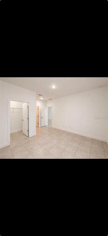An empty room with light-colored tile flooring, white walls, and an open walk-in closet — 9130 N MENDOZA WAY, CITRUS SPRINGS, FL