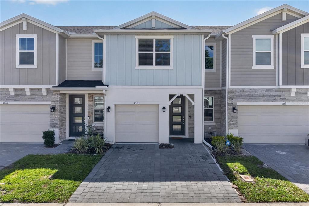 A three-story townhouse exterior features a paved driveway, a garage, and light blue siding — 1363 CAPTIVA COVE, SANFORD, FL