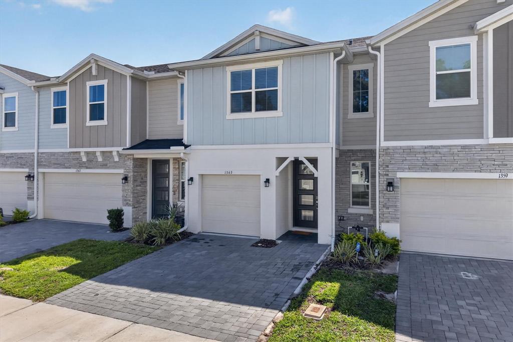 A row of three modern townhouses features stone veneer, light-colored siding, and paved driveways — 1363 CAPTIVA COVE, SANFORD, FL