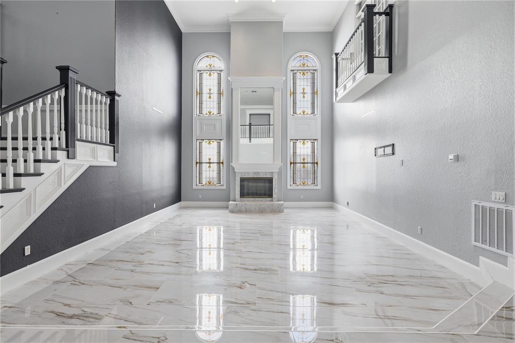 A high-ceilinged living room features marble floors, a fireplace, stained-glass windows, and a staircase — 3017 OAKMONT DRIVE, CLEARWATER, FL