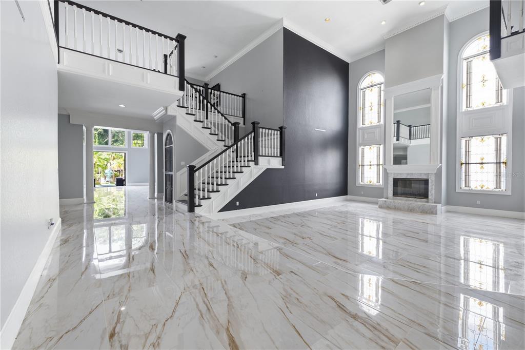 A spacious living room features a grand staircase, marble floors, and a tall fireplace — 3017 OAKMONT DRIVE, CLEARWATER, FL