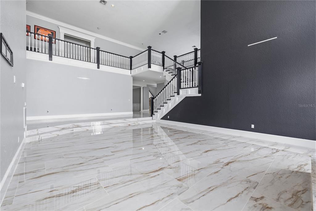 A grand foyer features a dark wood staircase, marble flooring, and an interior balcony — 3017 OAKMONT DRIVE, CLEARWATER, FL