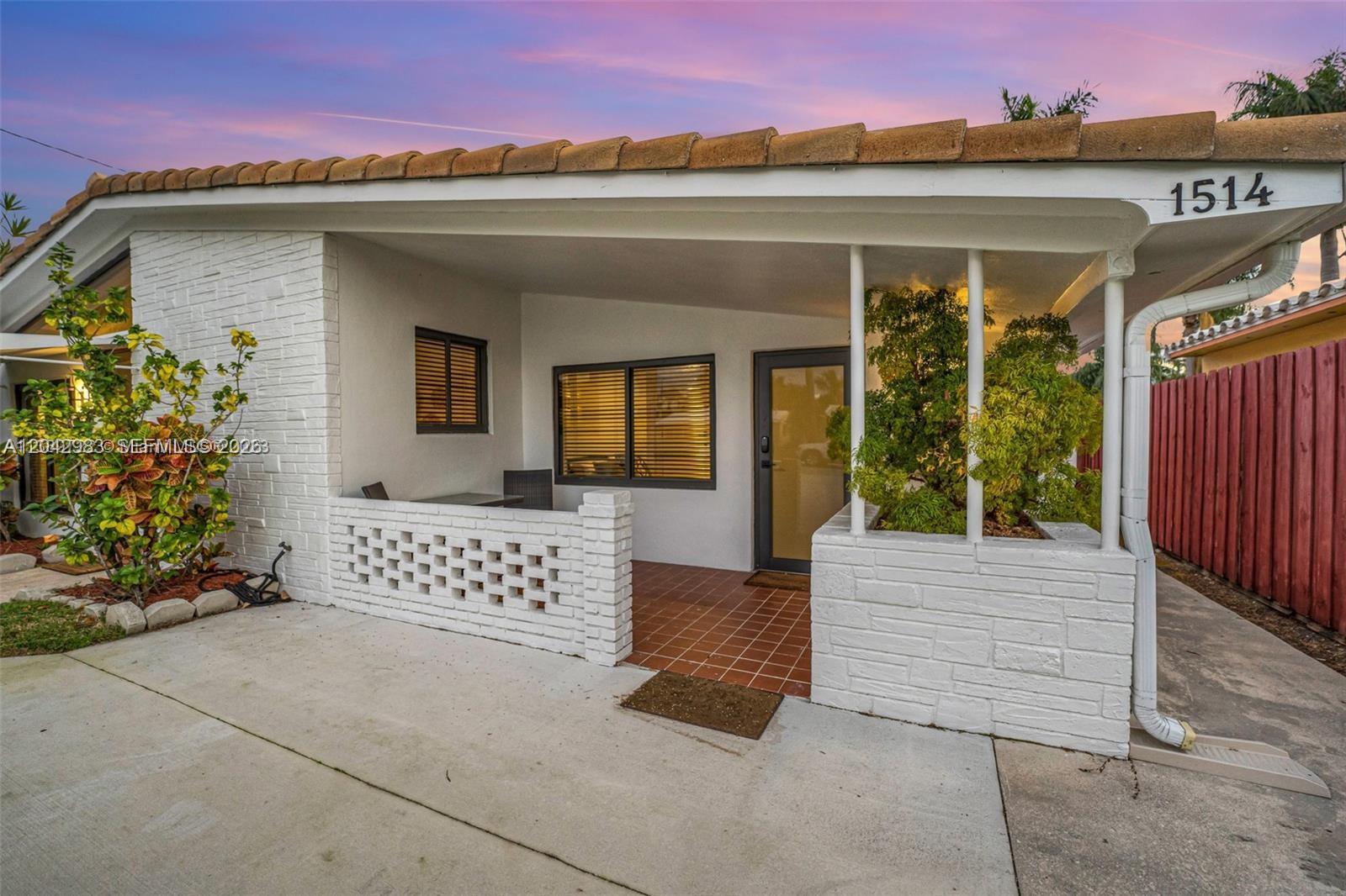 The exterior of a single-story home features a white brick facade, tiled porch, and roof — 1514 Liberty St, Hollywood FL 33020, HOLLYWOOD, FL