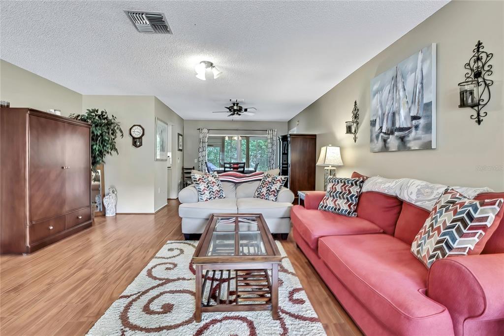 A living room features a red sofa, a white loveseat, and a glass-topped coffee table — 6517 OCEAN PINES LANE, SPRING HILL, FL