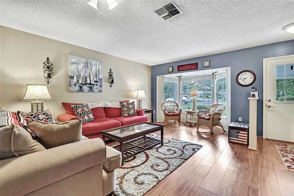 A living room features a red sofa, a beige armchair, and a bay window area — 6517 OCEAN PINES LANE, SPRING HILL, FL