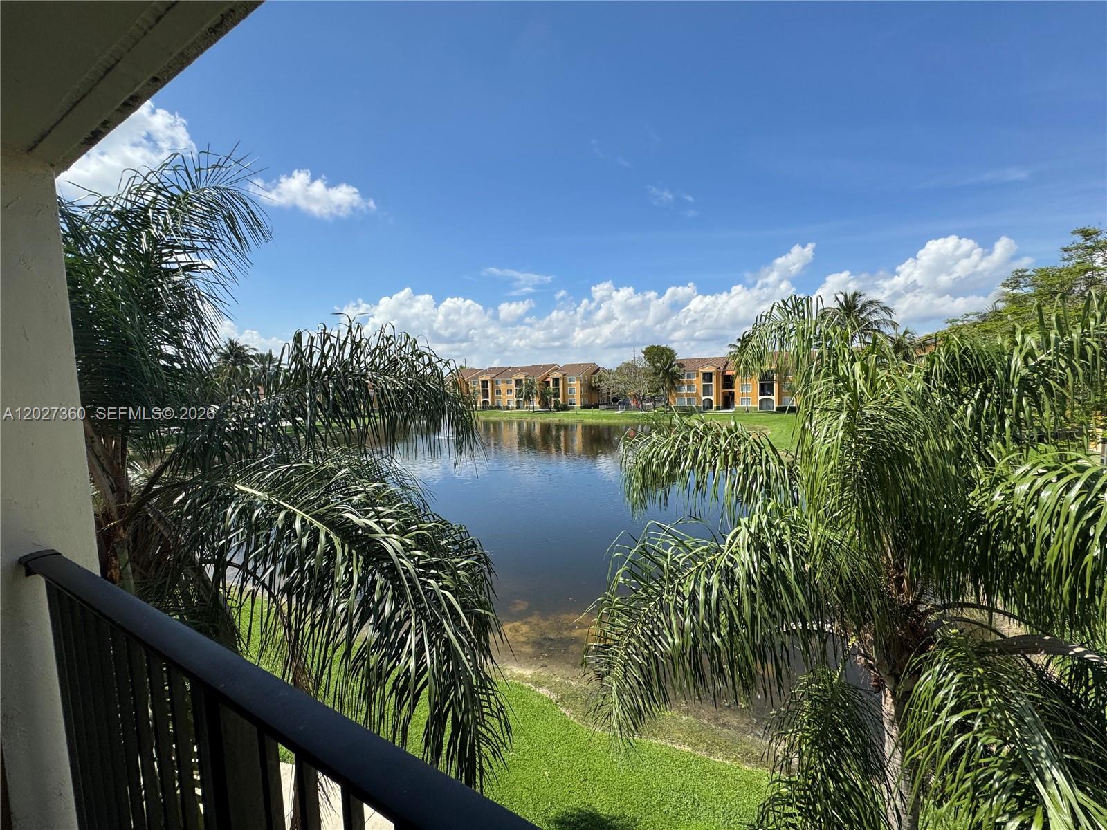 A balcony view overlooks a lake surrounded by palm trees and apartment buildings — 2200 E Preserve Way # 308, Miramar FL 33025, MIRAMAR, FL
