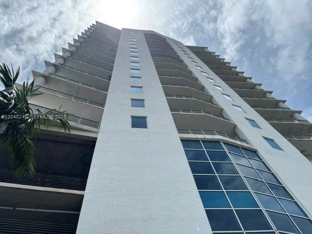 A low-angle view of a tall, white residential high-rise building with balconies and glass windows — 10 SW South River Dr # 1109, Miami FL 33130, MIAMI, FL
