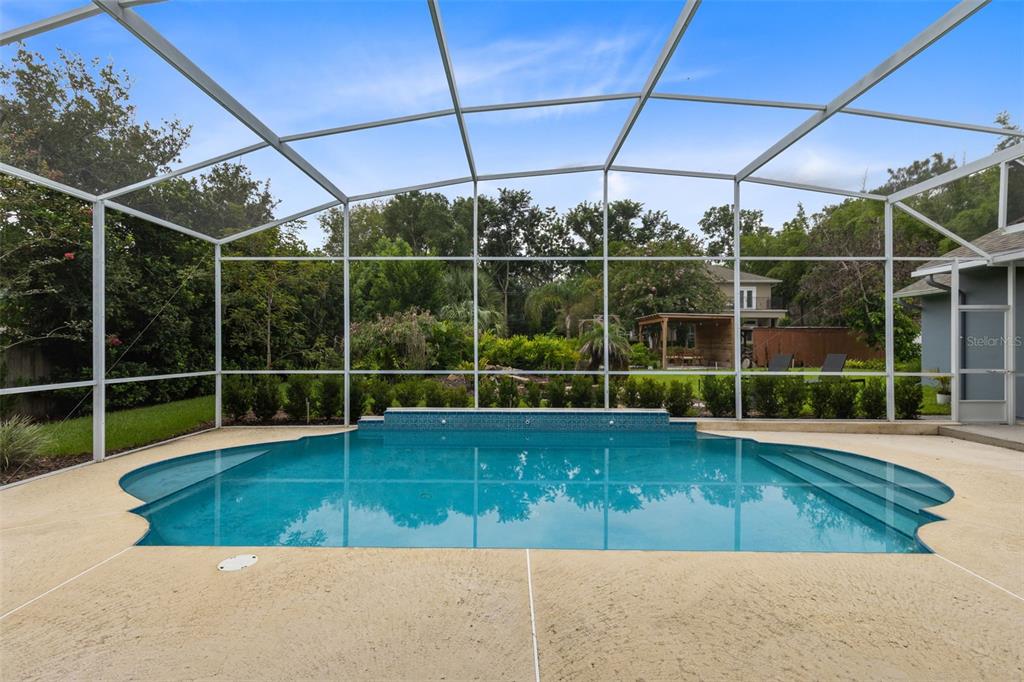 A screened-in swimming pool with a tiled water feature sits on a concrete patio — 113 SANDY OAKS PLACE, LONGWOOD, FL