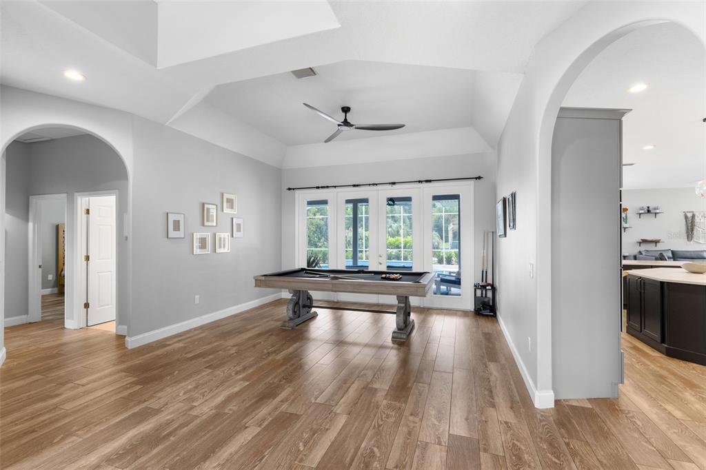 A game room features a pool table, wood-look flooring, and glass doors leading outside — 113 SANDY OAKS PLACE, LONGWOOD, FL