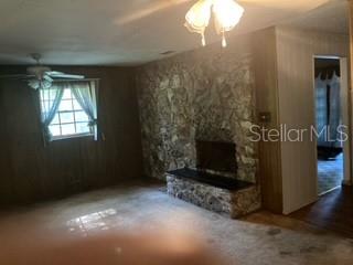 A living room features wood-paneled walls, a stone fireplace, and a ceiling fan — 13814 NW 158TH AVENUE, ALACHUA, FL