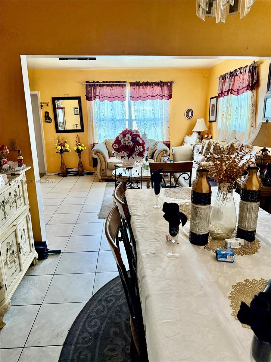A dining room with a set table leads into a living room with yellow walls — 1180 NW 46th Ave, Lauderhill FL 33313, LAUDERHILL, FL