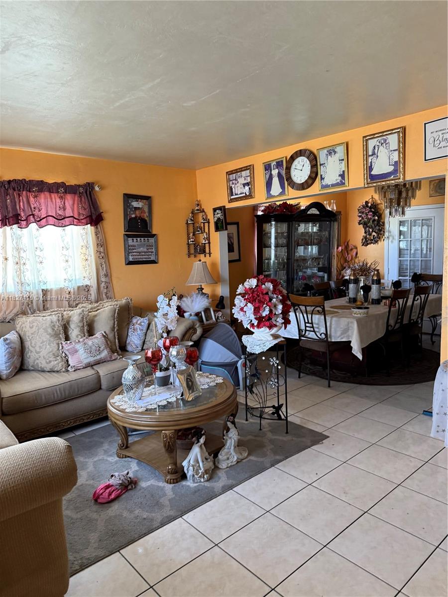 A living room with orange walls, a beige sofa, and a dining area in the background — 1180 NW 46th Ave, Lauderhill FL 33313, LAUDERHILL, FL