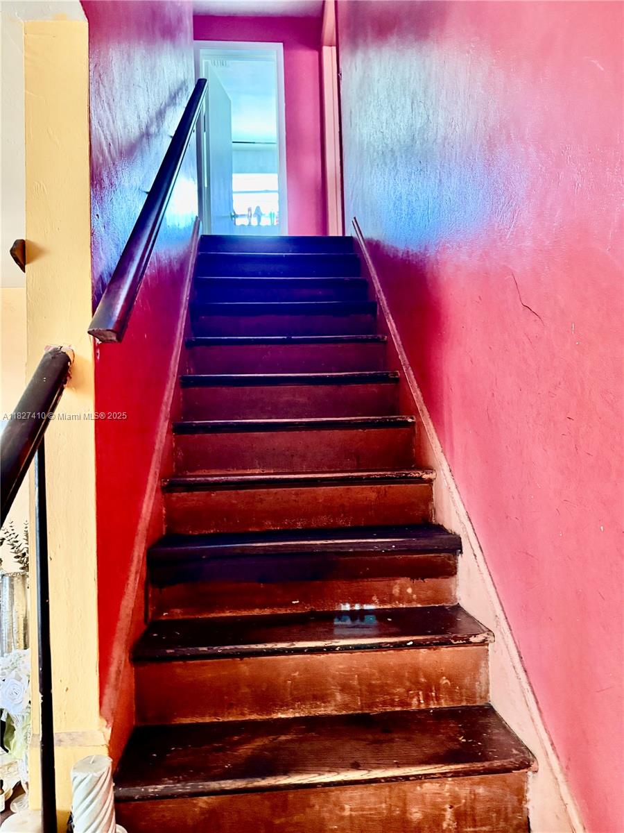 A staircase with dark wooden treads leads upward between bright pink walls — 1180 NW 46th Ave, Lauderhill FL 33313, LAUDERHILL, FL