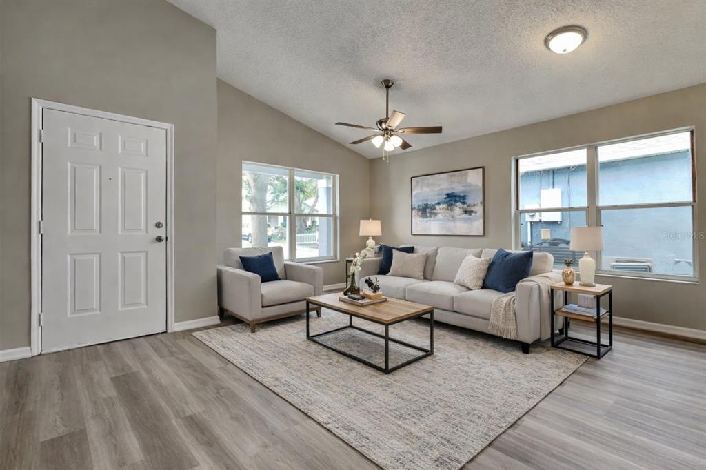 A living room features light gray walls, wood-look flooring, a sofa, an armchair, and windows — 1226 FREMONT PARK AVENUE, ORLANDO, FL