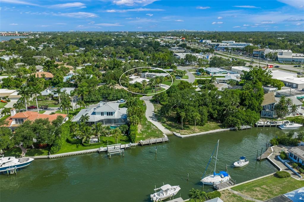 An aerial view shows a waterfront residential area with a circled house and docked boats — 7616 COVE TERRACE, SARASOTA, FL