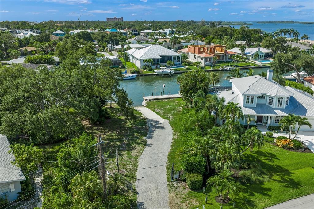An aerial view of a waterfront property with a gravel driveway leading to a boat dock — 7616 COVE TERRACE, SARASOTA, FL