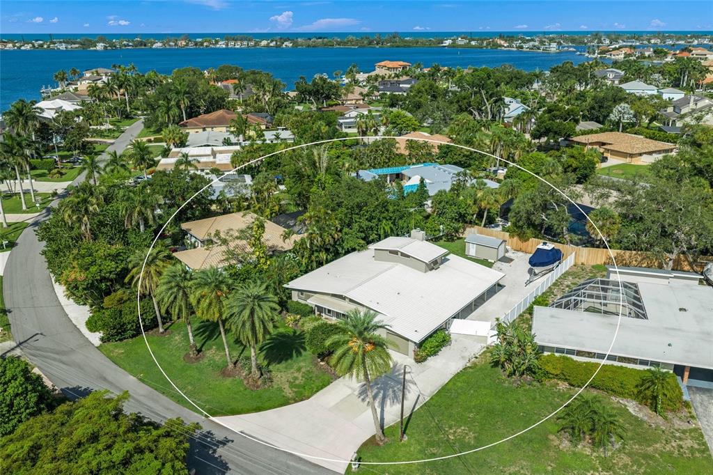 An aerial view shows a single-story house with a white roof, palm trees, and driveway — 7616 COVE TERRACE, SARASOTA, FL