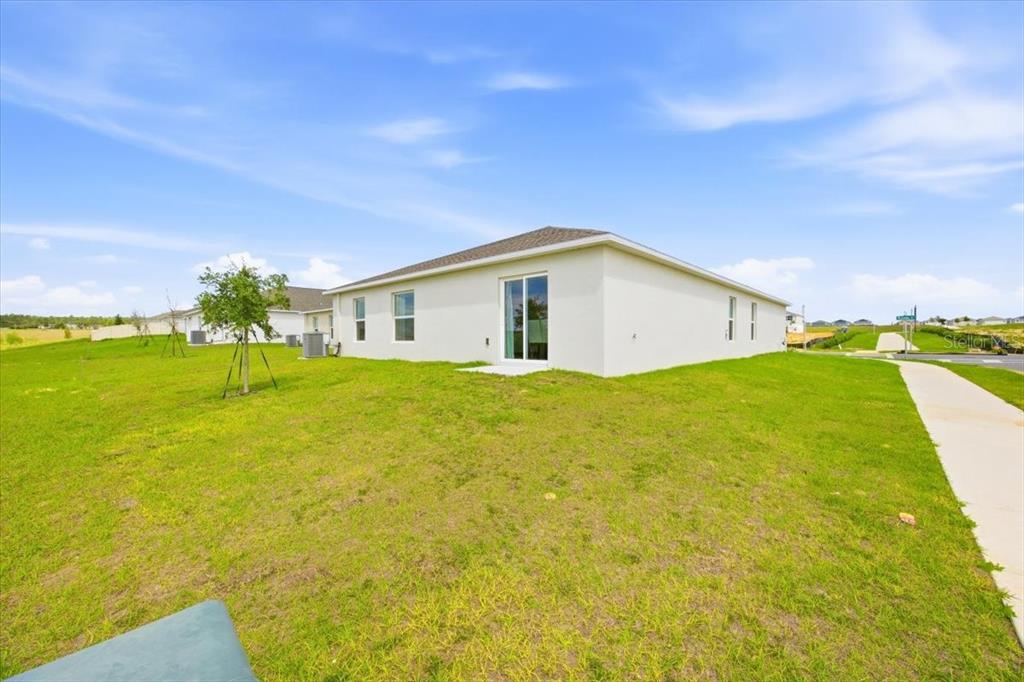 The exterior of a light-colored, single-story house features a sliding glass door and grassy yard — 2350 MCKINLEY DRIVE, LAKE WALES, FL