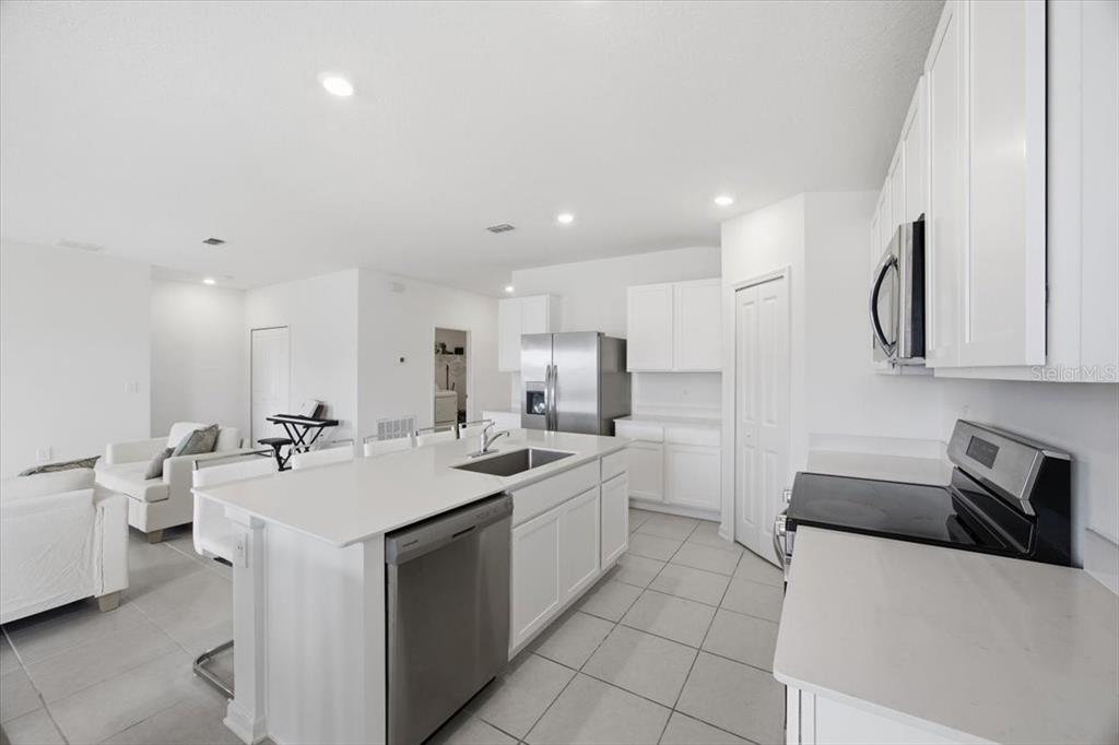 A modern kitchen with white cabinets, stainless steel appliances, and a large island with seating — 2350 MCKINLEY DRIVE, LAKE WALES, FL
