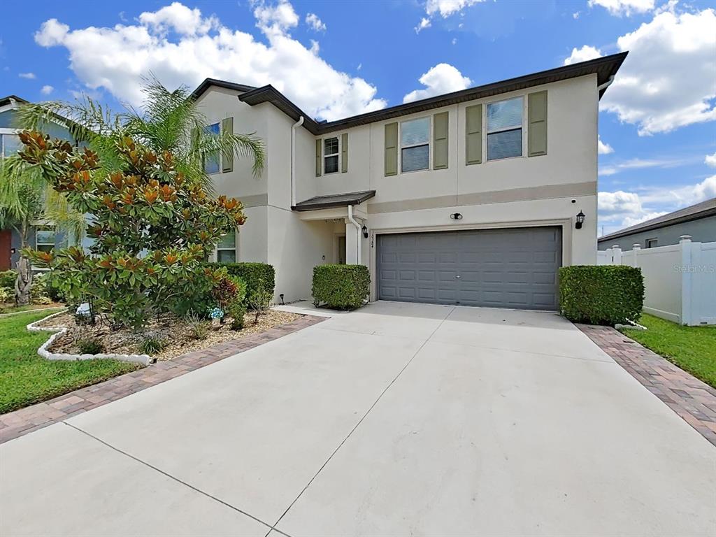 A two-story suburban house features a concrete driveway, a two-car garage, and manicured landscaping — 10384 SCARLET SKIMMER, RIVERVIEW, FL