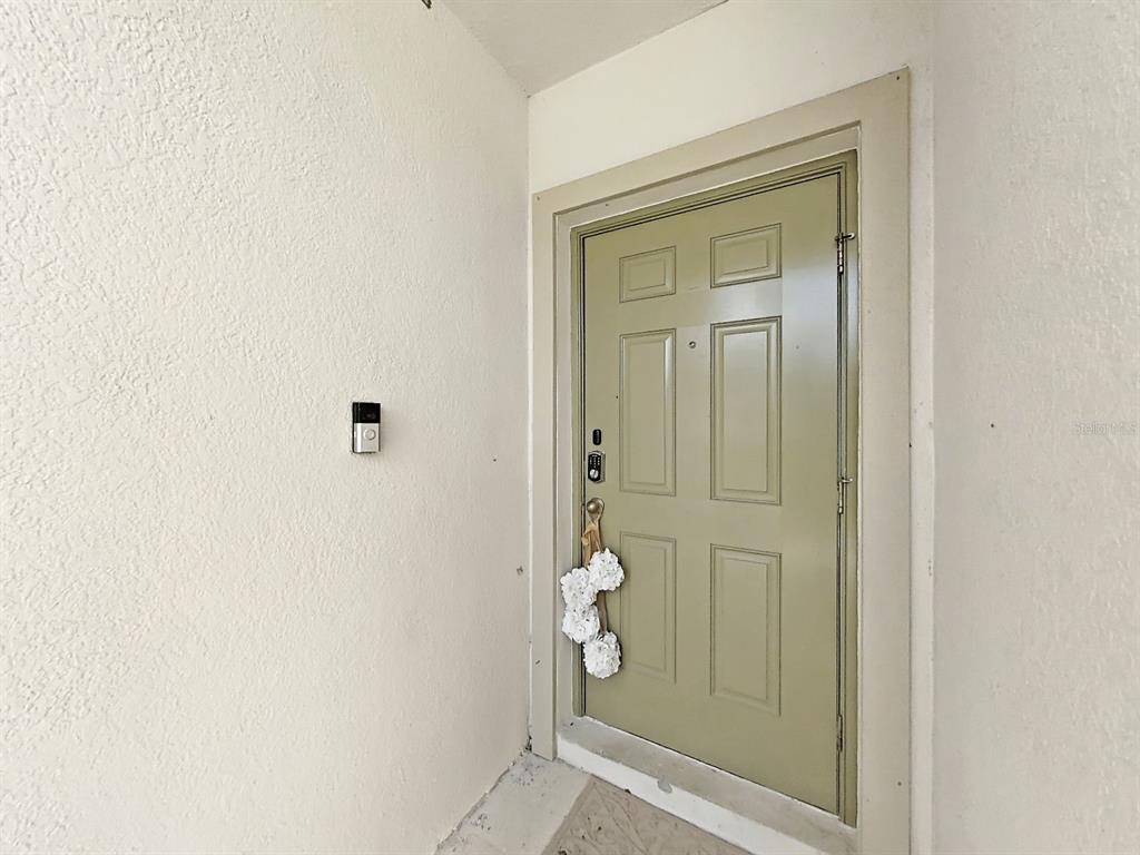 A light green front door with a smart lock and doorbell camera on a porch — 10384 SCARLET SKIMMER, RIVERVIEW, FL