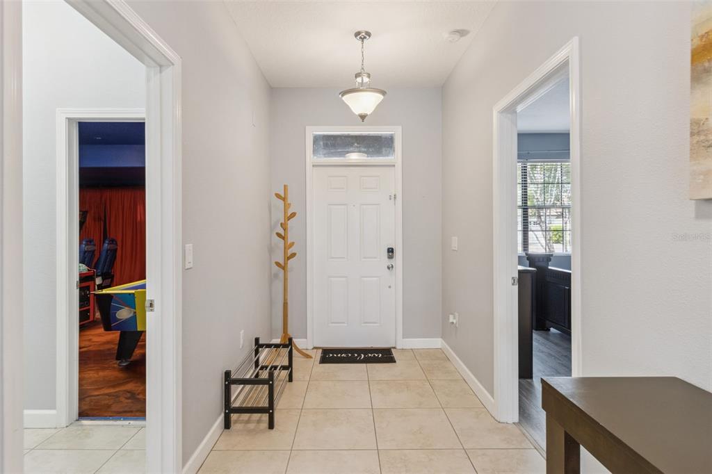 A tiled entryway features a white front door, a coat rack, and two doorways — 9027 SHADOW MOUNTAIN STREET, DAVENPORT, FL