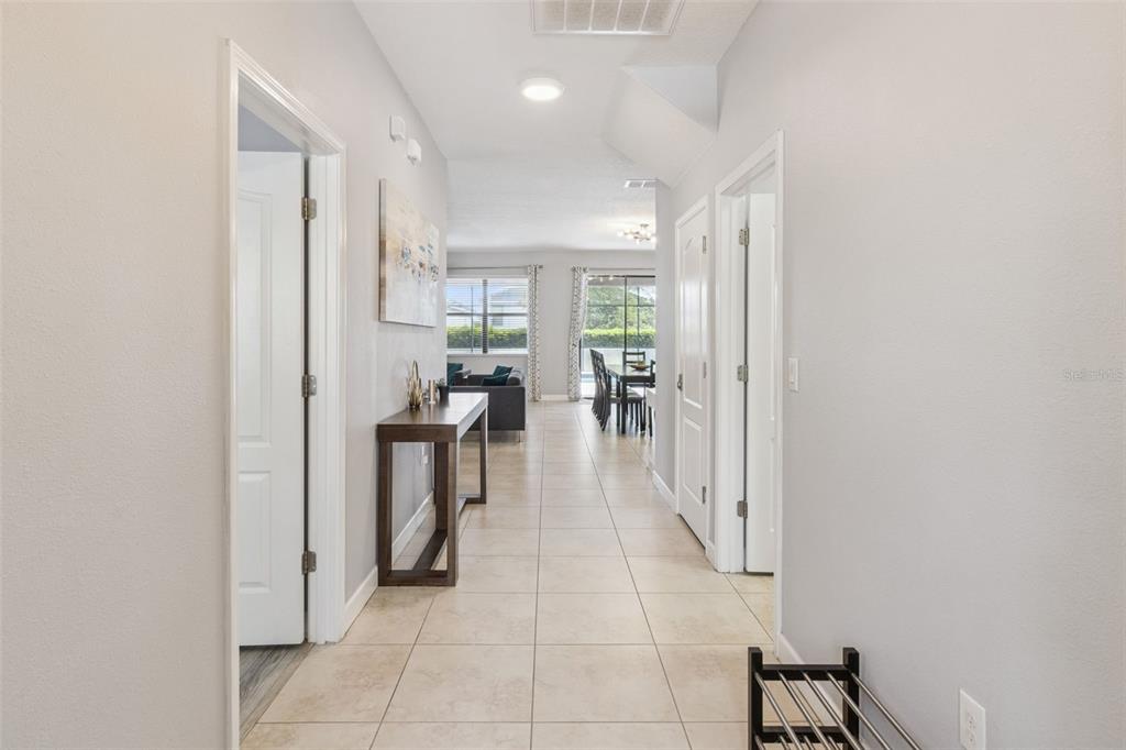 A tiled hallway leads past interior doors toward a living and dining area with windows — 9027 SHADOW MOUNTAIN STREET, DAVENPORT, FL