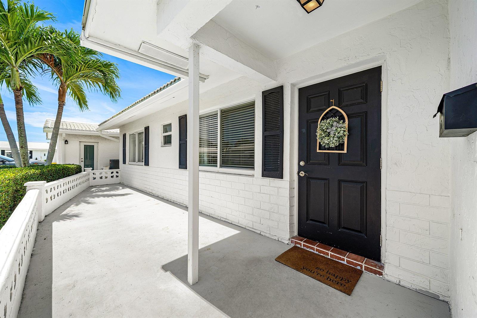 A white brick house exterior features a black front door with a wreath and porch — 2105 SW 14th Place, Boynton Beach FL 33426, BOYNTON BEACH, FL