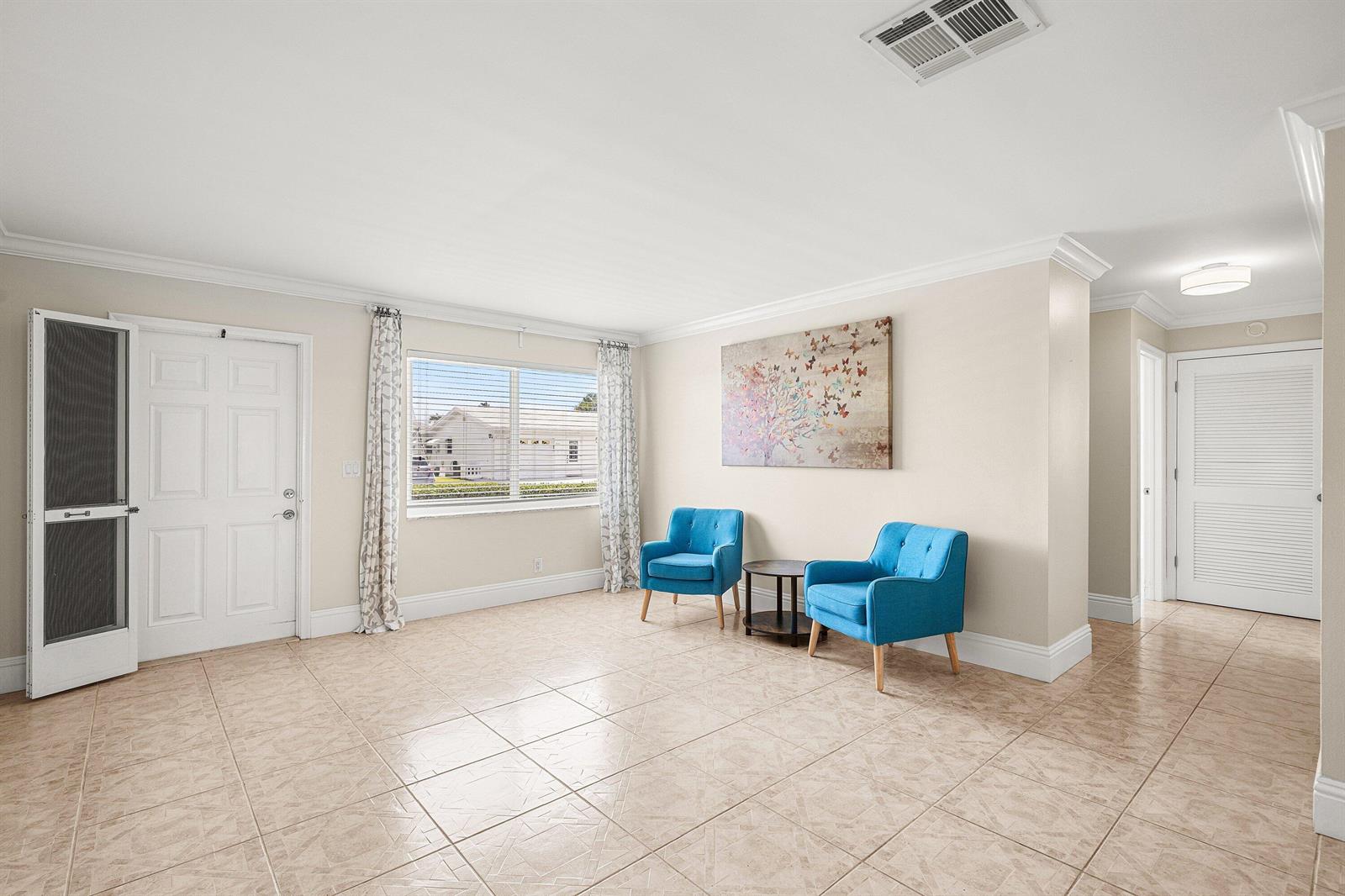 A living room features beige tile floors, two blue armchairs, and a butterfly wall painting — 2105 SW 14th Place, Boynton Beach FL 33426, BOYNTON BEACH, FL