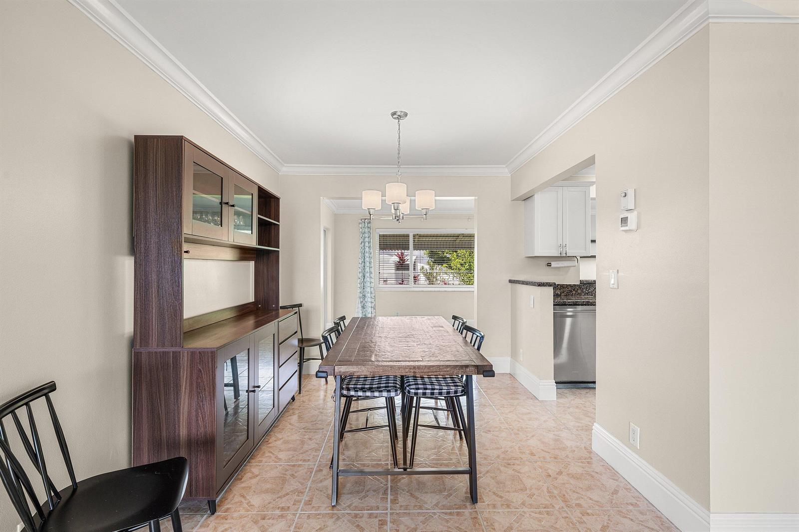 A dining room with a wooden table, hutch, and tiled floor adjacent to a kitchen — 2105 SW 14th Place, Boynton Beach FL 33426, BOYNTON BEACH, FL